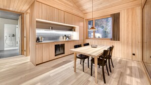 A modern kitchen with wooden cabinetry, a stainless steel range, and a dining area with a wooden table and chairs.