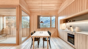A modern kitchen with wooden cabinetry, a central island, and a large window offering a view of snow-capped mountains.