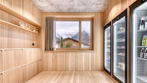 A wooden interior with a large window, wooden shelves, and two refrigerators.