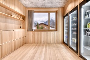 A wooden interior with a large window, wooden shelves, and two refrigerators. - Appartmentshaus Studa 29 Studa 10 (Brand)