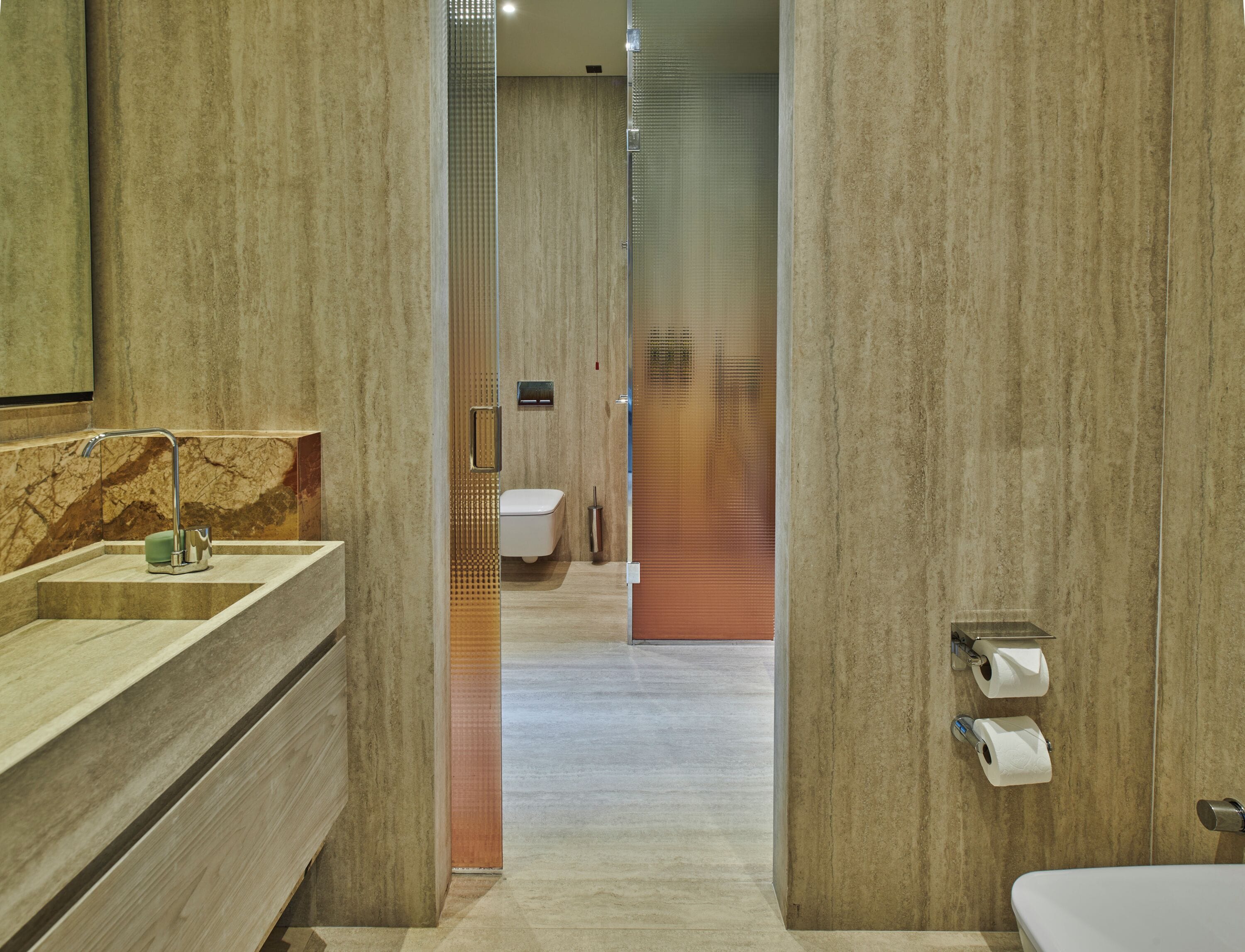 Un baño moderno con lavamanos de mármol, inodoro y zona de ducha.