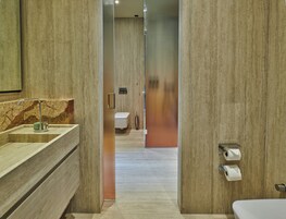 Un baño moderno con lavamanos de mármol, inodoro y zona de ducha.
