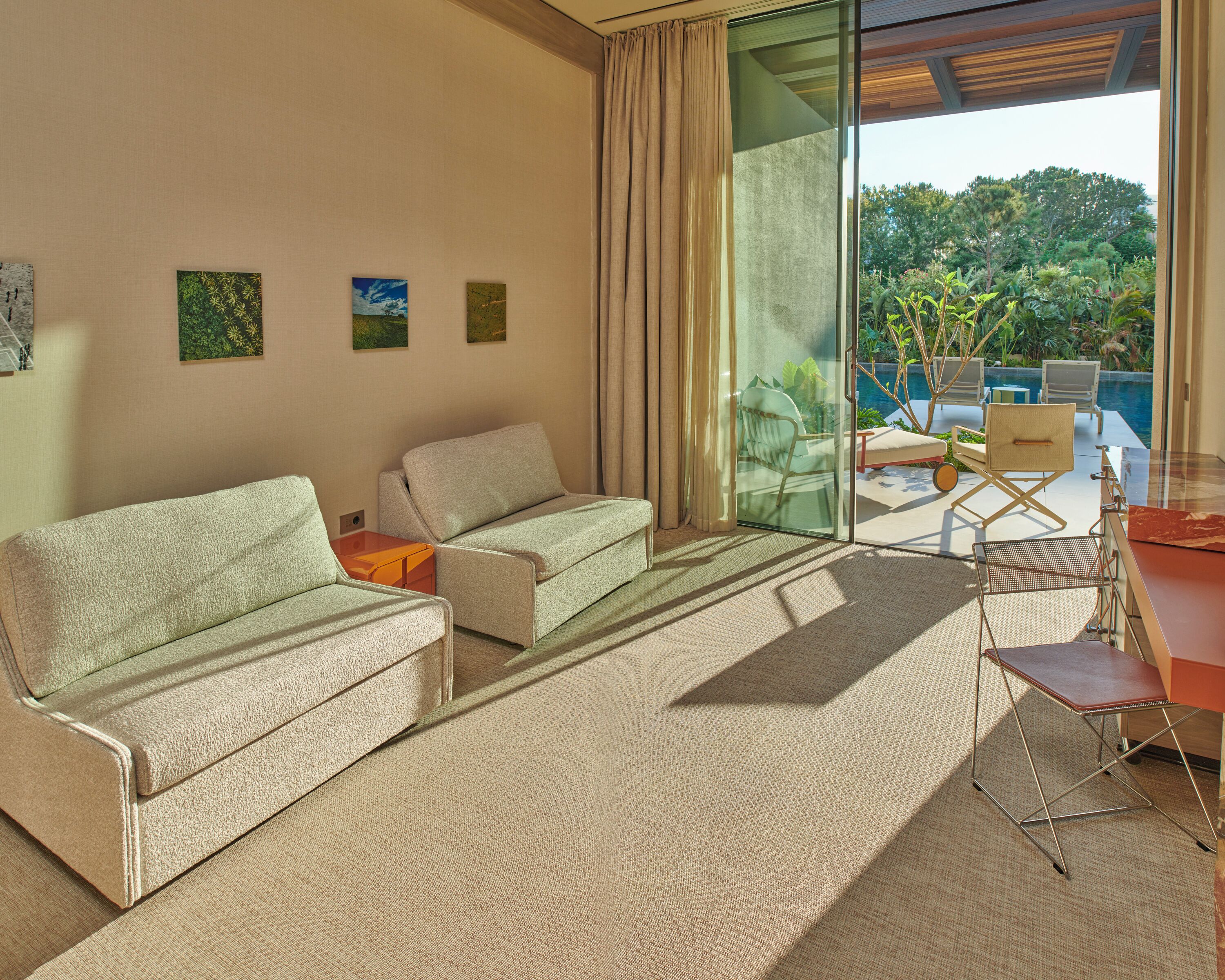 Ein modernes Wohnzimmer mit einer Couch, Sesseln und einer Glastür, die auf einen Balkon mit einem Pool führt.