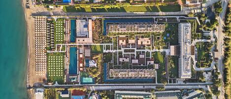 An aerial view of a resort with multiple swimming pools, a beach, and various recreational facilities.