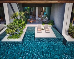 A modern outdoor pool area with lounge chairs and a seating area.