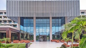 Un edificio moderno con fachada de vidrio, entrada central y zonas de estar al aire libre.