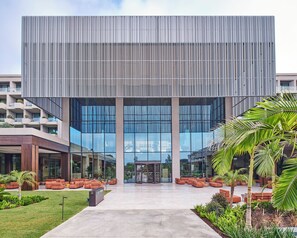 A modern building with a glass facade, a central entrance, and outdoor seating areas. - Voyage Kundu (Antalya)