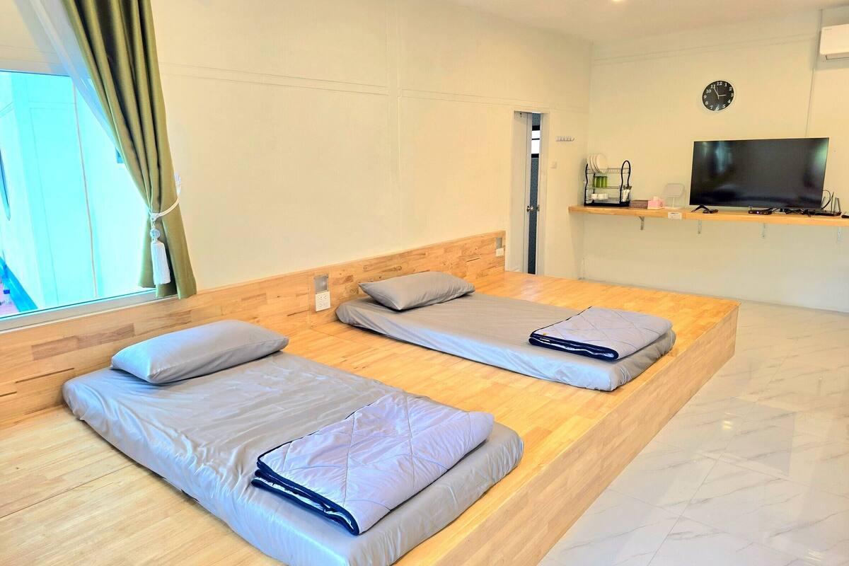 A hotel room with two beds, a TV, and a wooden floor.
