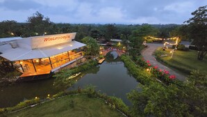 Un hôtel situé au bord de la rivière, doté d’un espace de restauration avec vue sur l’eau, d’un petit pont et d’un chemin de jardin bien éclairé.