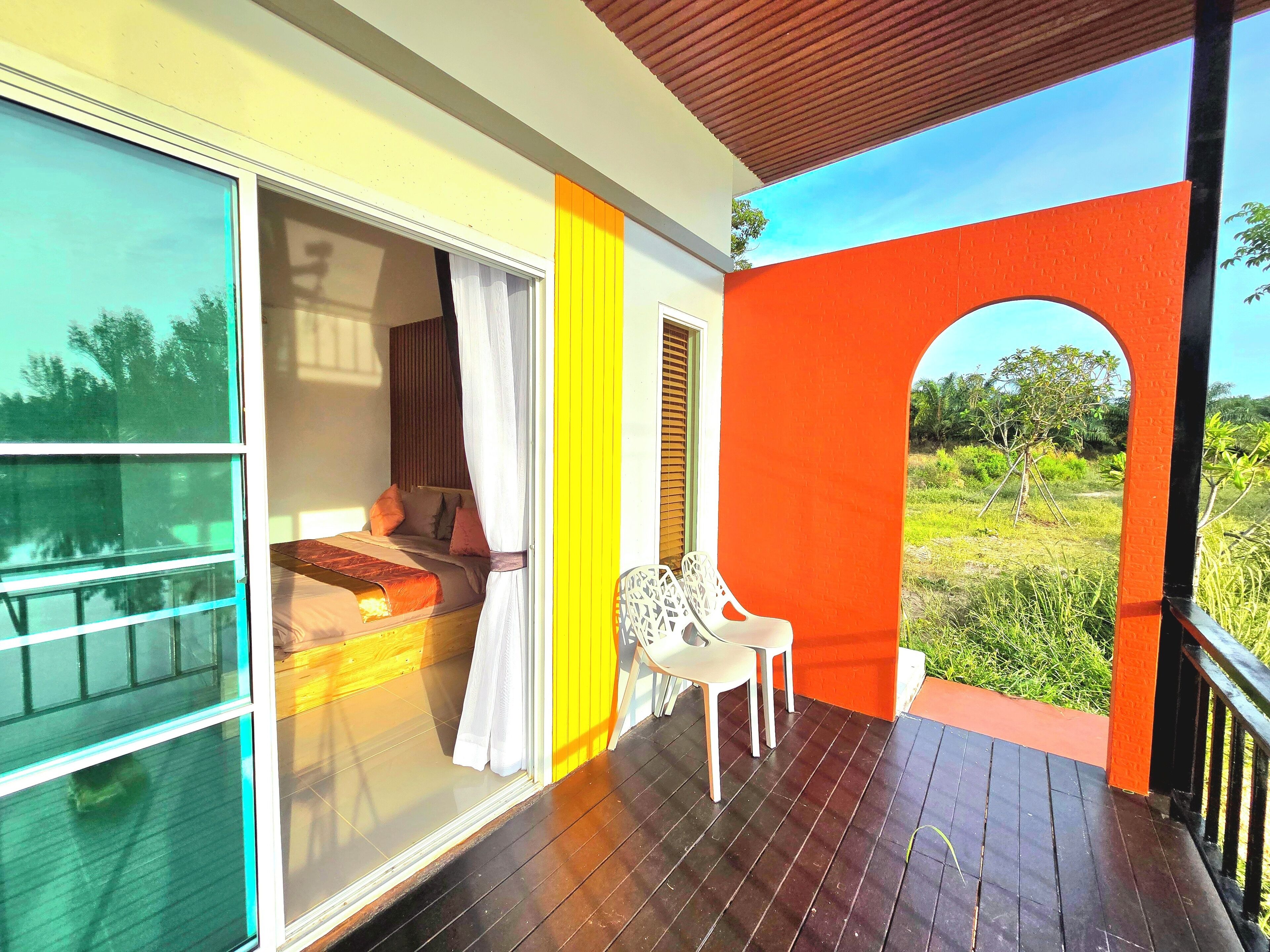 Una habitación con una cama, un ventanal y vistas al verdor exterior.