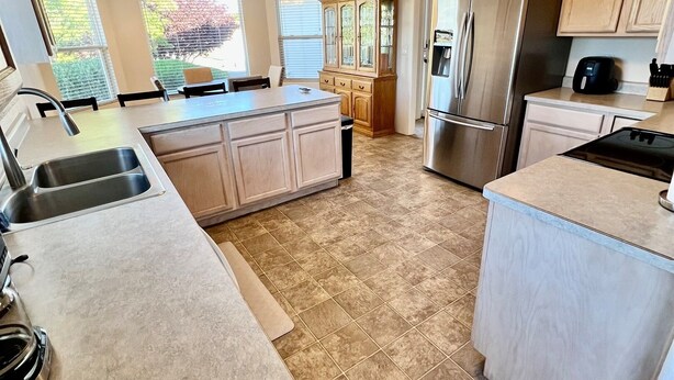 A spacious kitchen with a central island, stainless steel appliances, and light-colored cabinetry. - Large Prescott Home w/3-car Garage Central & Quiet (Prescott)
