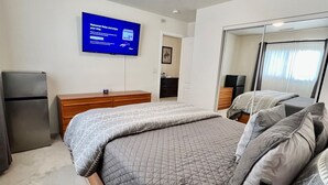 A hotel room with a bed, bedside table, lamp, TV, and a mirror. - Large Prescott Home w/3-car Garage Central & Quiet (Prescott)