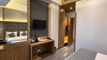 A modern hotel room with a large bed, a desk, a flat-screen TV, and a ceiling fan.