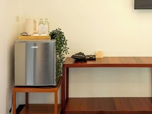 Une petite cuisine équipée avec un réfrigérateur en acier inoxydable, une petite table en bois et une plante en pot.