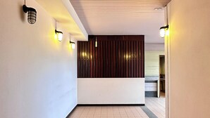 Un pasillo con pared de listones de madera, paredes blancas y suelo de baldosas.