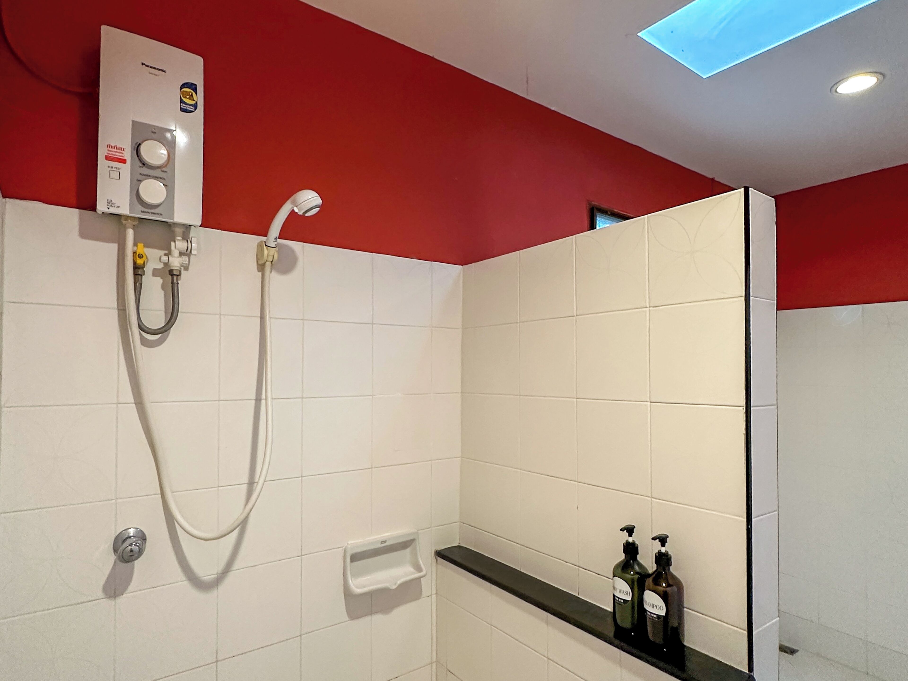 Ein modernes Badezimmer mit Dusche, Seifenspender und zwei Shampoo-Flaschen.