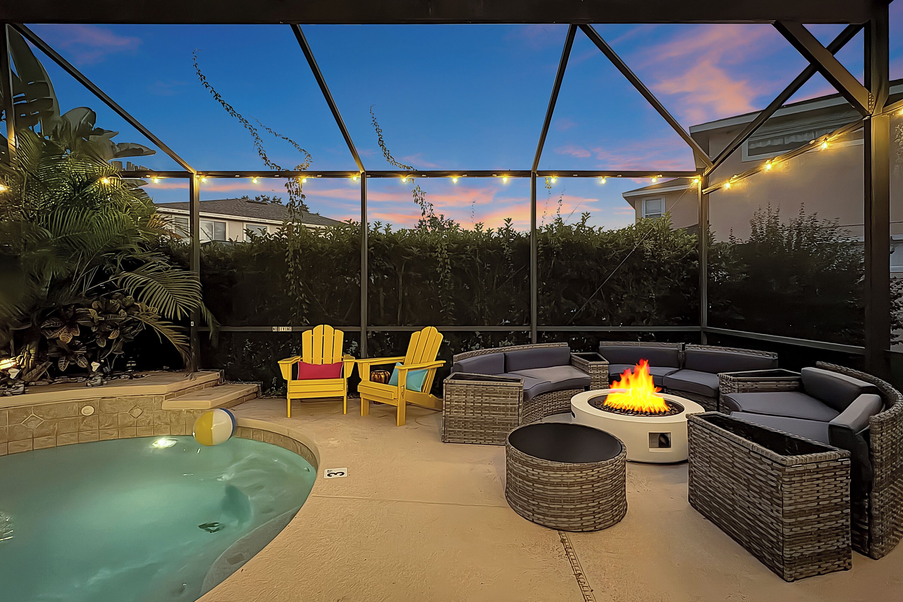 An outdoor patio with a pool, seating, and a fire pit.