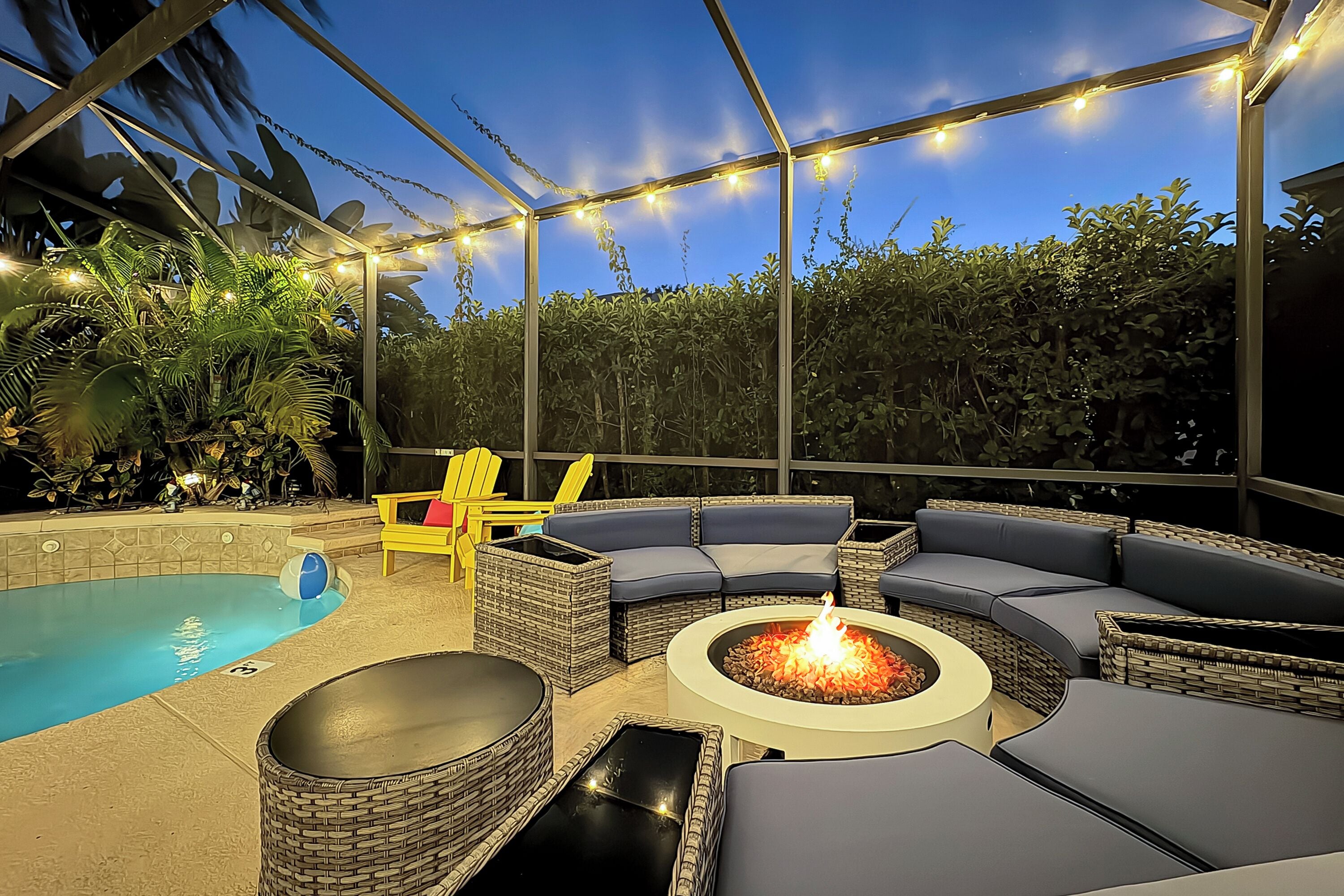 An outdoor patio with a pool, lounge seating, and a fire pit.