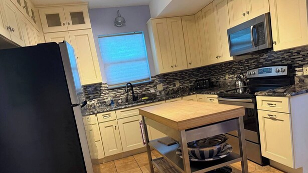 A kitchen with white cabinets, a black refrigerator, a stove, and a microwave. - Minutes away from the beach and walking distance into town (St. Augustine)