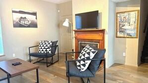 A living room with two armchairs, a coffee table, a fireplace, and a television. - Minutes away from the beach and walking distance into town (St. Augustine)