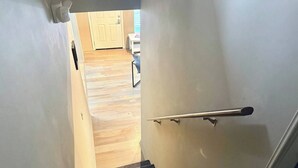 A staircase with a handrail, carpeted steps, and a wooden floor leading to a room with a door and a table. - Minutes away from the beach and walking distance into town (St. Augustine)