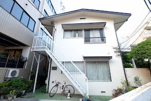 A two-story building with a white exterior, a balcony on the second floor, and a bicycle parked outside. - Yumenoya Yoyogi (Tokyo)