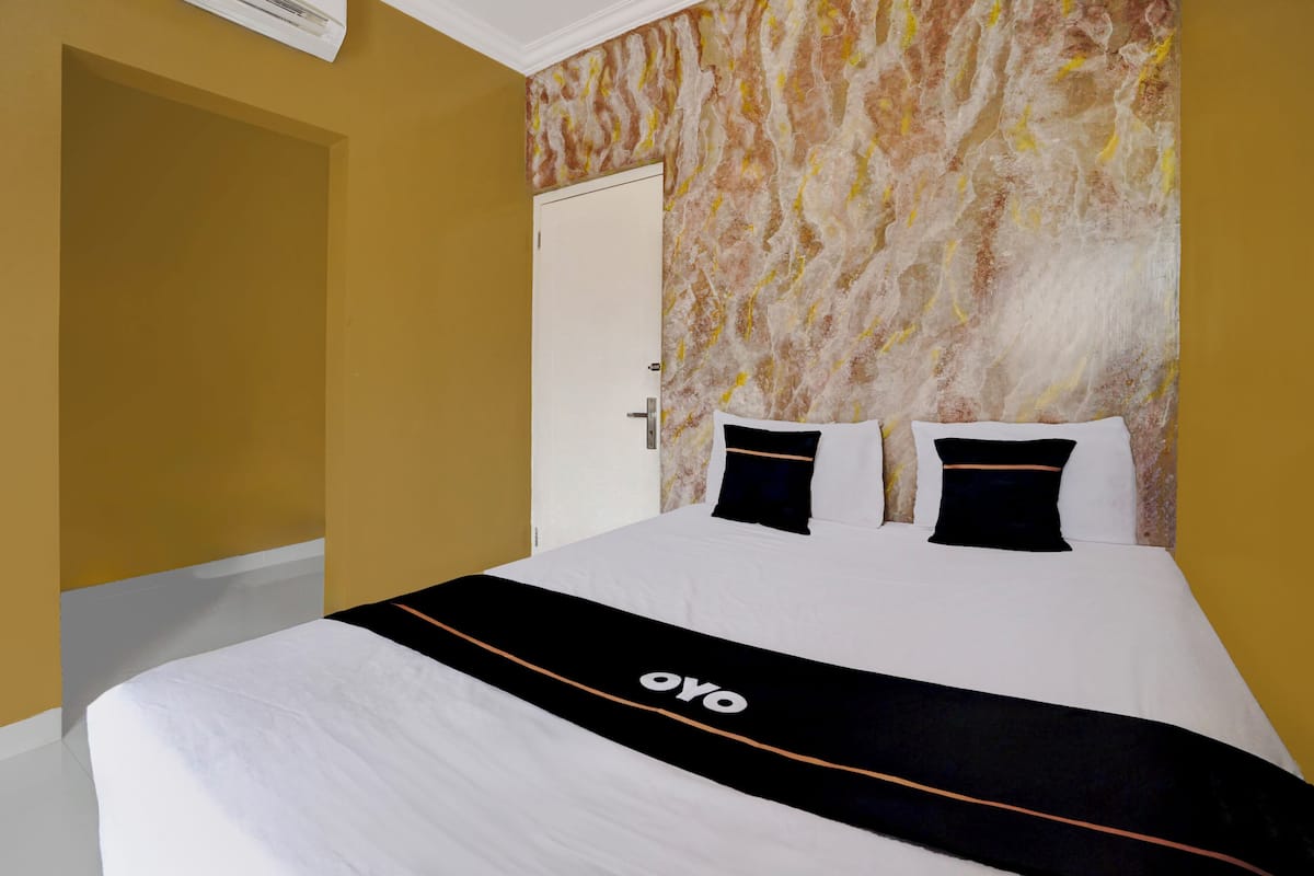 Ein Hotelzimmer mit einem Bett, einer Wand mit Marmoroptik und einer Tür.