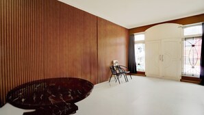 A spacious room with a large round table and chairs, a wooden slat wall, and a large white door with glass panels. - Hotel O Omah Bratan (Malang)