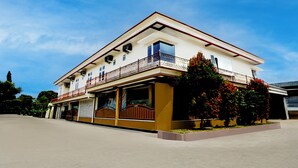 A two-story building with a balcony, a garage, and a garden with red flowers. - Hotel O Omah Bratan (Malang)