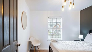 A bedroom with a bed, a chair, a window with blinds, a lamp, and a door. - ‼️3BR Lakefront in Nashville w/ BBQ & Hot Tub (Nashville)