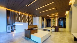 A modern lobby with a reception desk, seating areas, and a large plant.