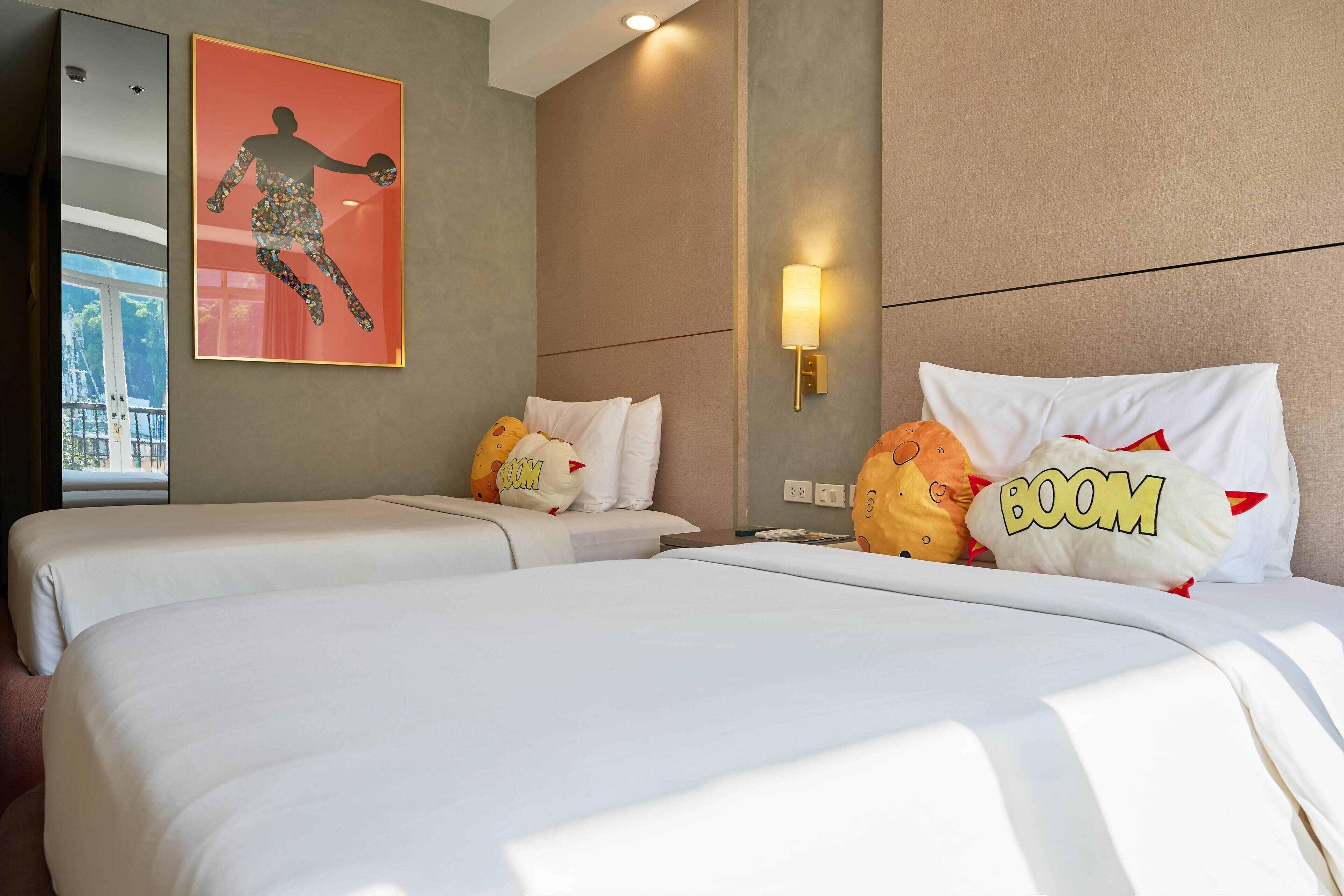 Une chambre d’hôtel avec deux lits, une grande fenêtre, une œuvre d’art accrochée au mur et un applique murale.