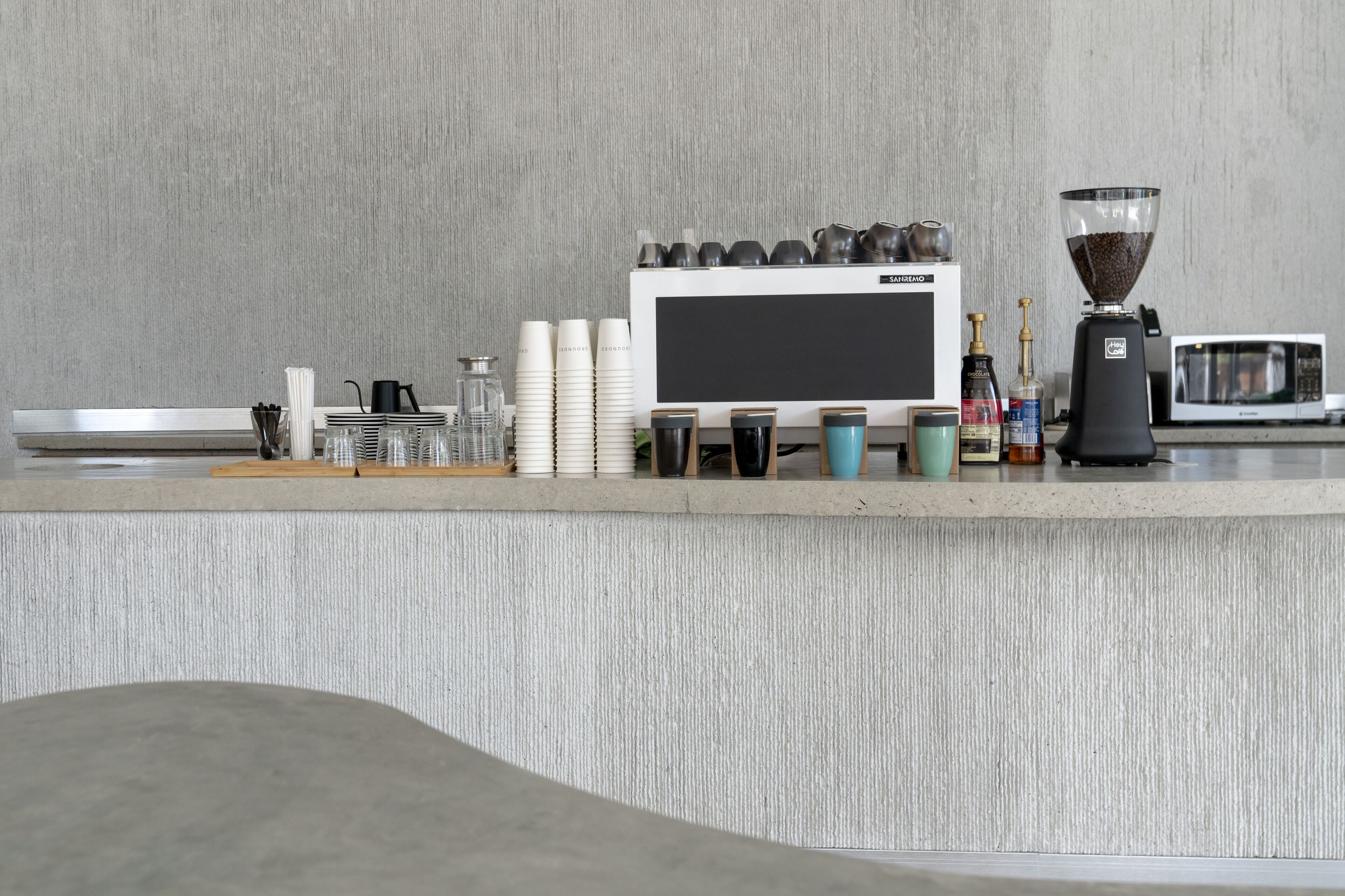 Una encimera de cocina con una cafetera, un microondas y diferentes utensilios de cocina.