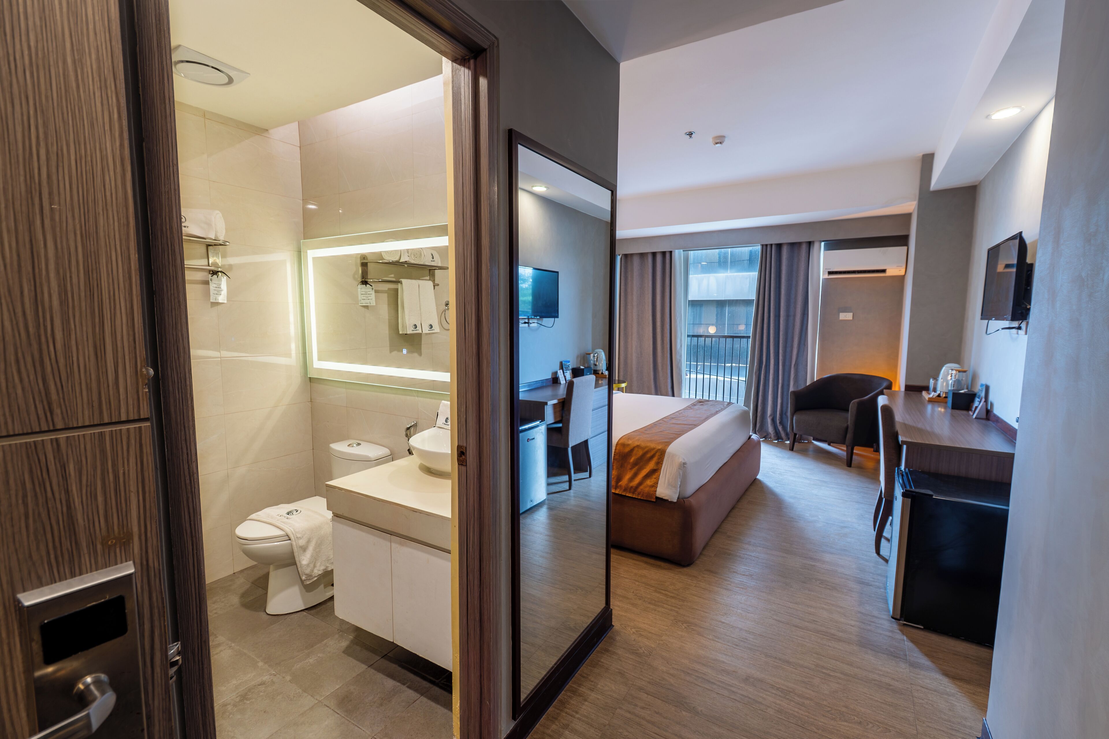 Une chambre d’hôtel avec salle de bain, un lit, un bureau et une télévision.