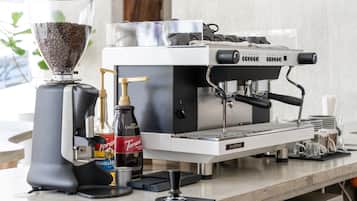 Una máquina de café con un molinillo, una botella de sirope Torani y una botella de sirope de vainilla.