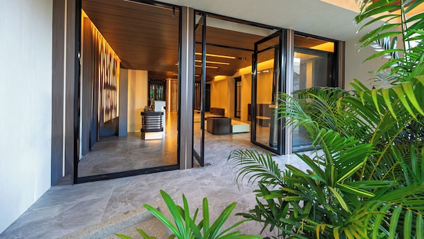 A modern interior with a glass door leading to a seating area and a plant in the foreground.