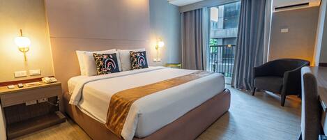A hotel room with a large bed, bedside tables, a desk, and a chair.