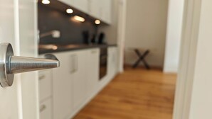A modern kitchen with white cabinets and a stainless steel handle on the door. - Deluxe Apartment No.03 with 2 bedrooms (Badenweiler)