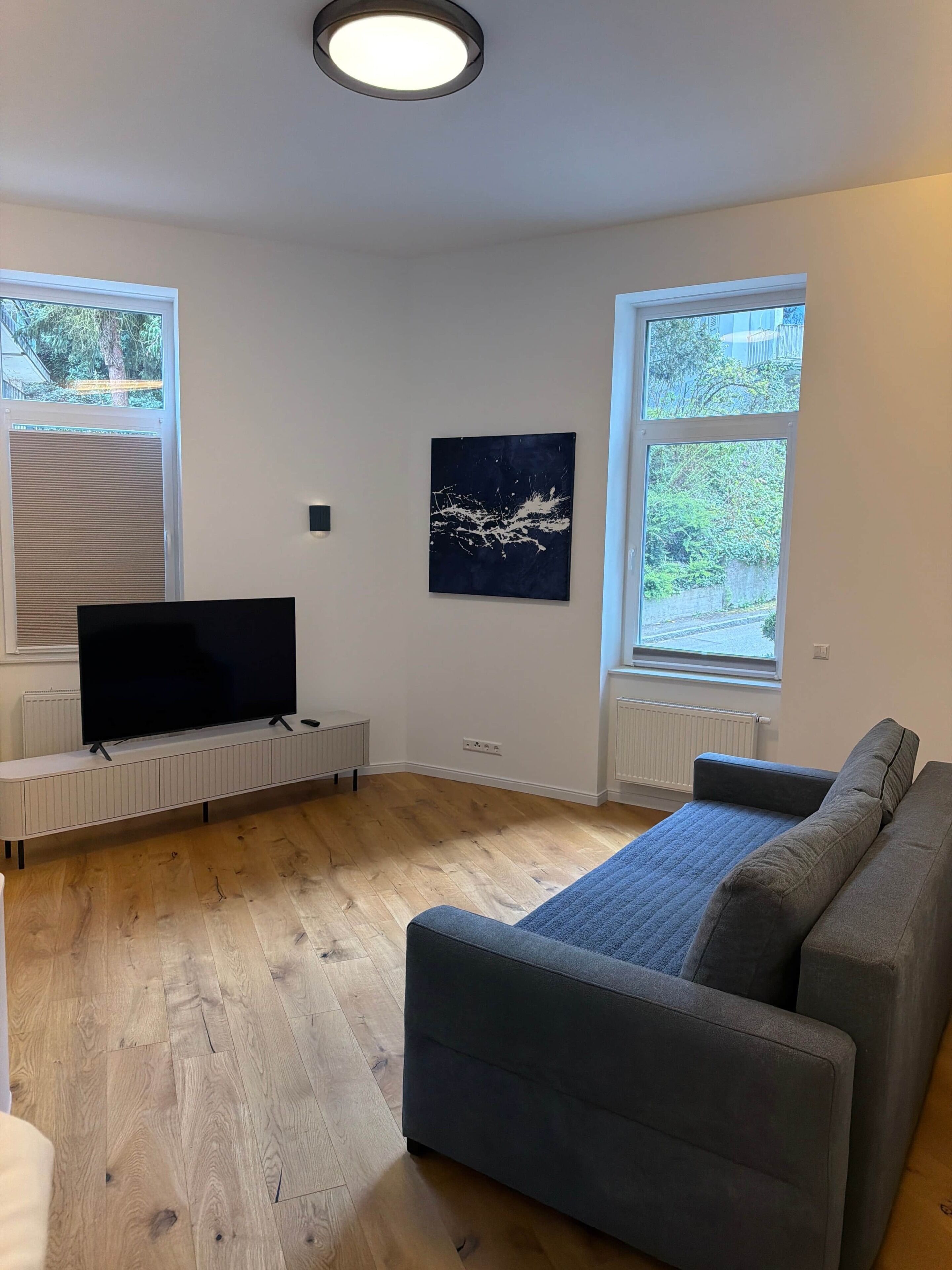 A modern living room with a flat-screen TV, a sofa, and a painting on the wall.