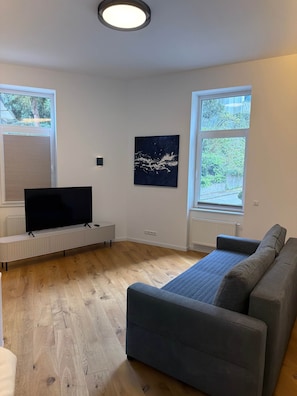 A modern living room with a flat-screen TV, a sofa, and a painting on the wall.