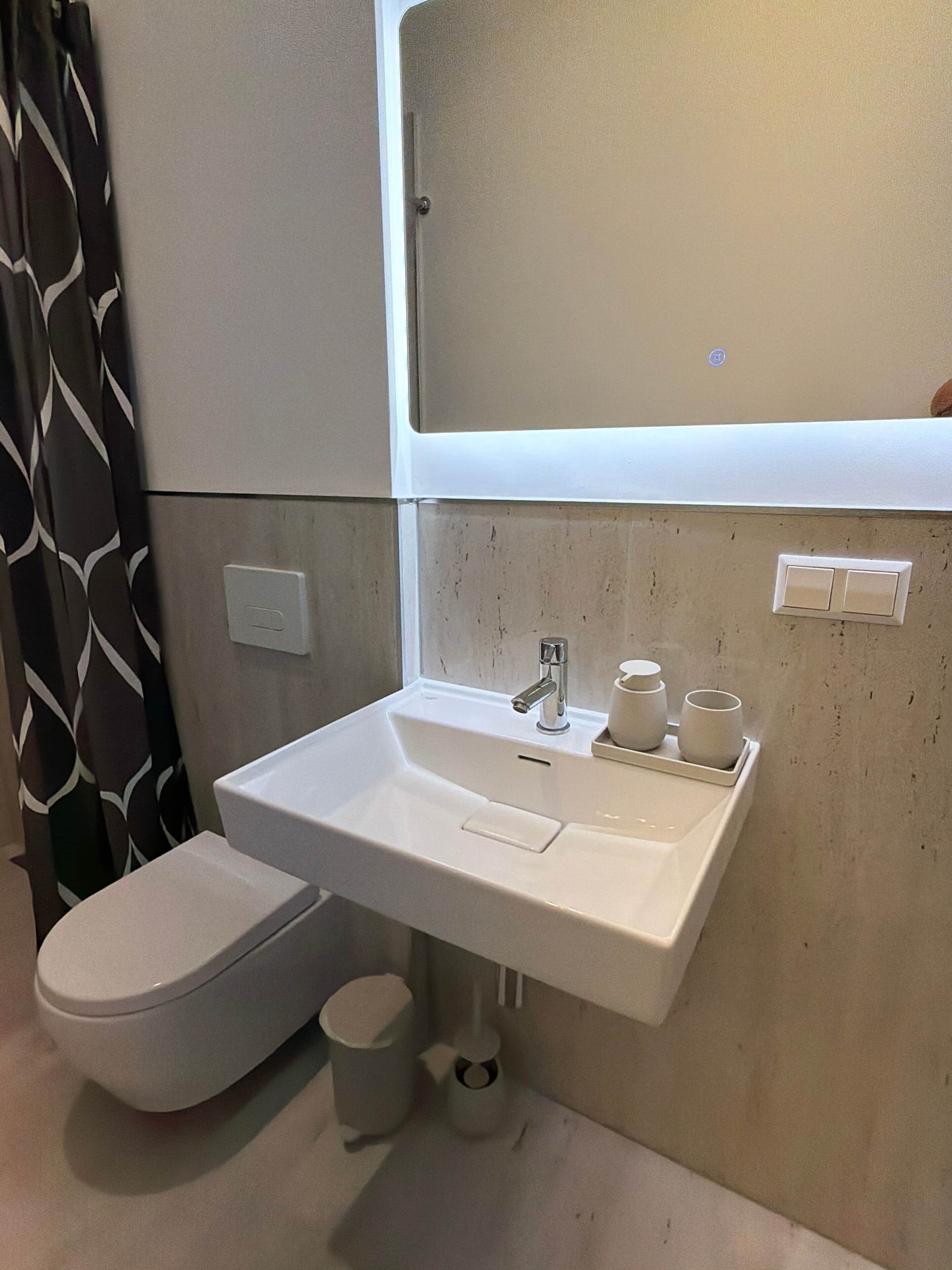 Une salle de bain avec des toilettes, un lavabo et un miroir au-dessus du lavabo.