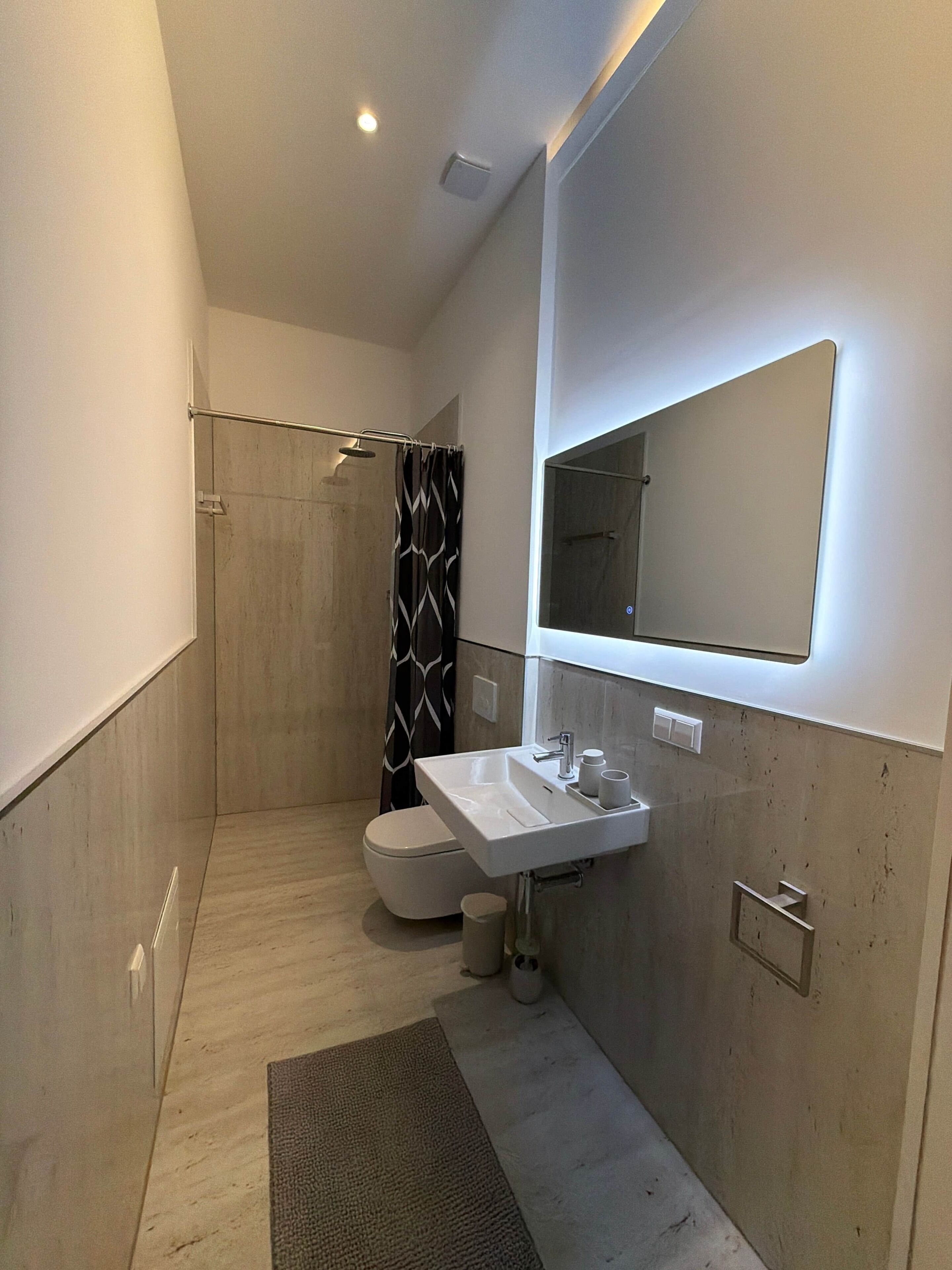 Een moderne badkamer met een douche, toilet en wastafel.