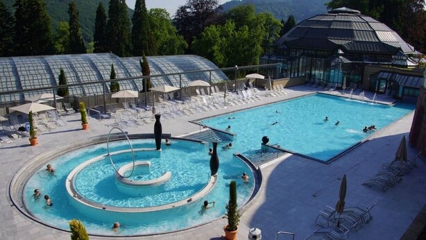 Uma área de piscina com várias piscinas, espreguiçadeiras e guarda-sóis.