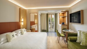 A hotel room with a large bed, a green sofa, a dining table, and a TV. - Villa Miliani (Fabriano)