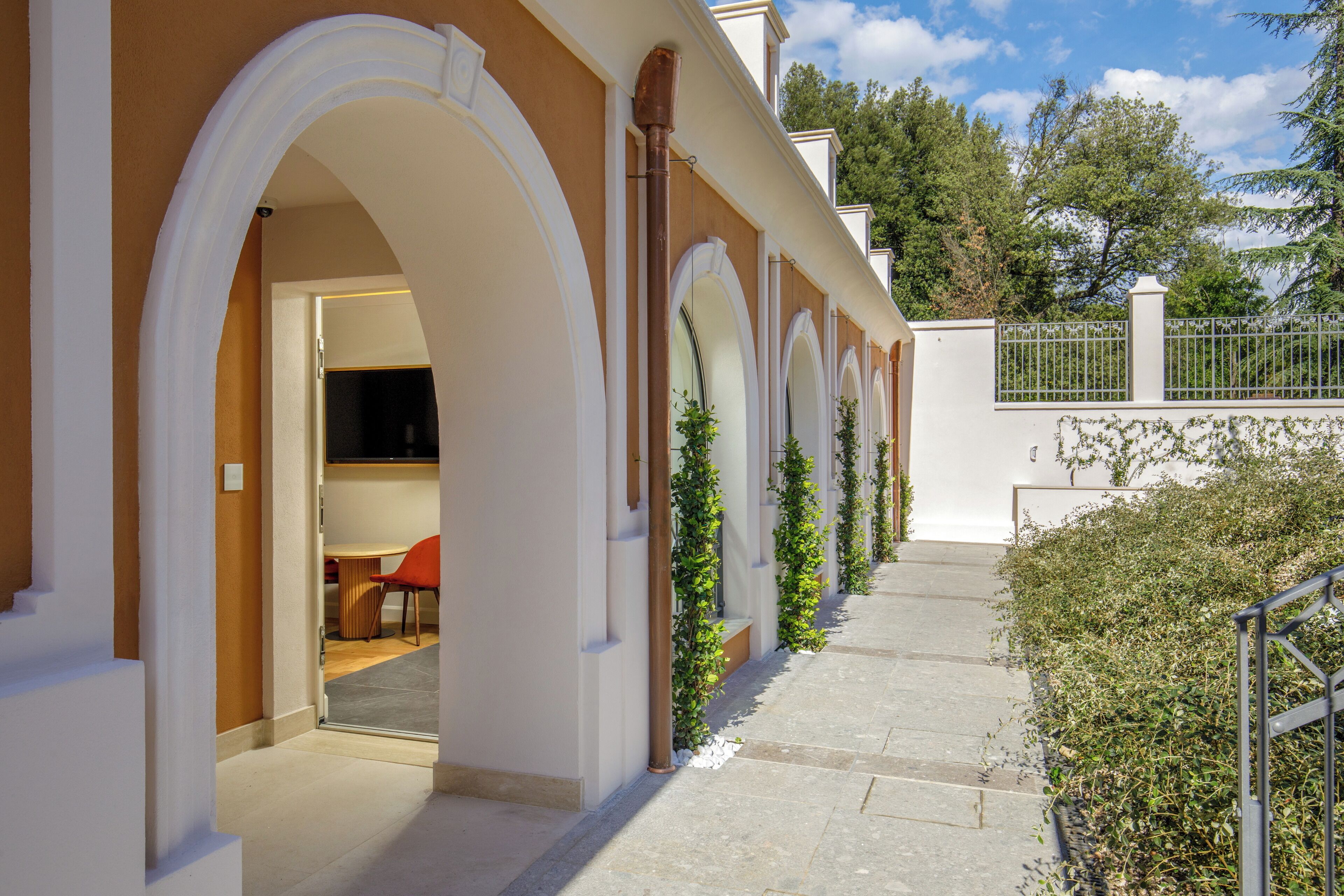 A building with arched doorways and a covered outdoor area with a staircase.