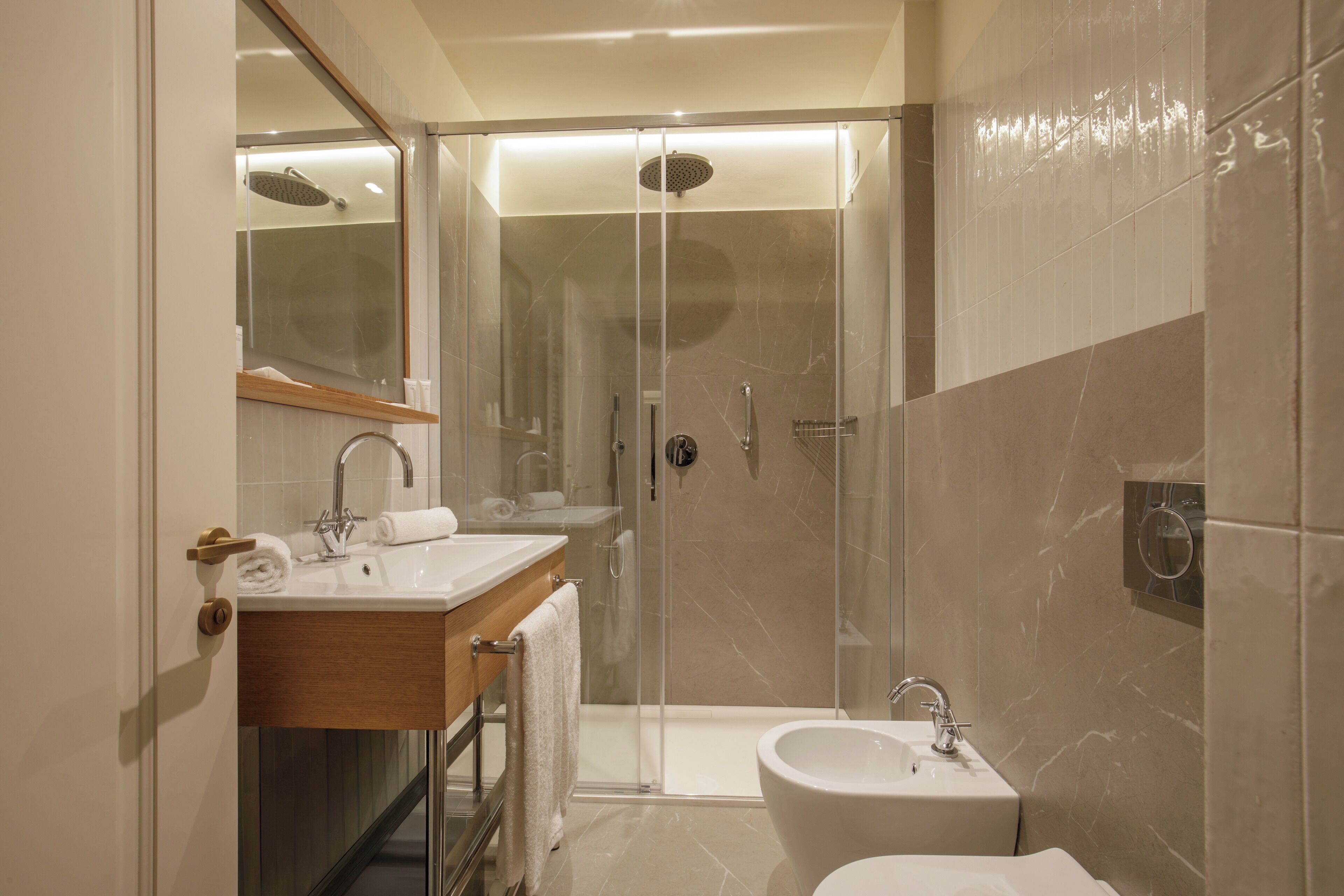 Une salle de bain moderne avec une douche à parois de verre, un meuble-lavabo avec un miroir et un lavabo séparé.