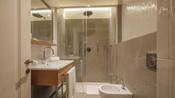 Une salle de bain moderne avec une douche à parois de verre, un meuble-lavabo avec un miroir et un lavabo séparé.