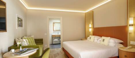 A modern hotel room with a large bed, a desk with a chair, and a small table with a vase and book.