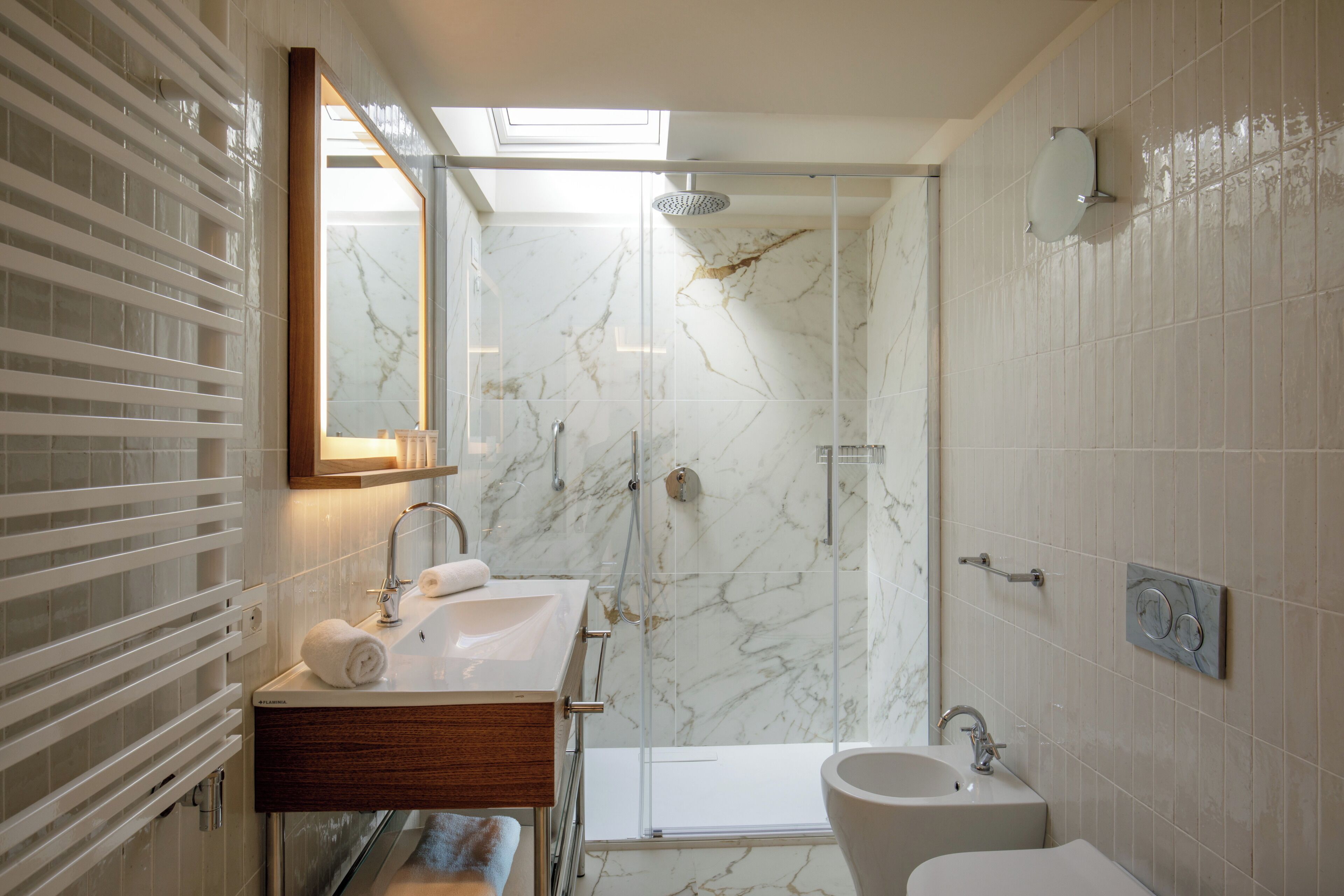 Un baño moderno con cabina de ducha de vidrio, tocador con encimera de mármol y un espejo grande.