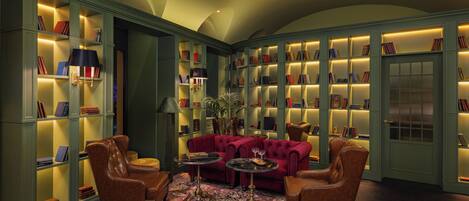 A library with bookshelves, a red sofa, and leather armchairs.